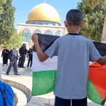 طفل فلسطيني يرفع علم فلسطين في وجه مجموعات مقتحمي المسجد الأقصى (مواقع التواصل)