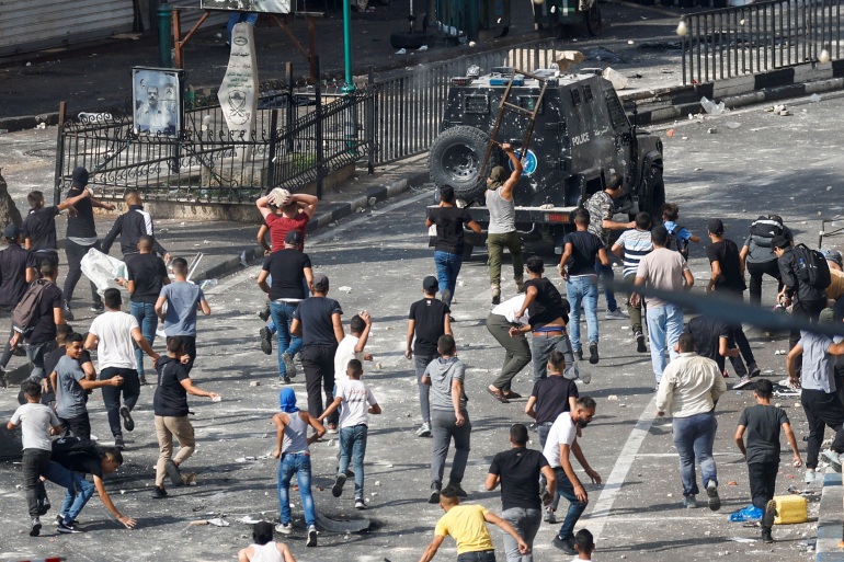 محتجون فلسطينيون يرشقون سيارة للأمن الفلسطيني وسط مدينة نابلس احتجاجا على اعتقال المطارد اشتية ورفيقه (رويترز)