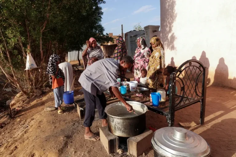 عائلات سودانية نازحة تنتظر الحصول على الطعام من مطبخ خيري في مدينة أم درمان بالسودان (رويترز)